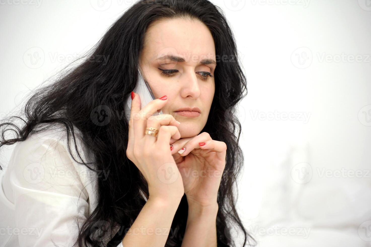 unpleasant conversation on phone brunette in hands with phone frowned lowered eyes woman upset sad seriously space for text problems at work health get sick coronavirus hospital breakup photo