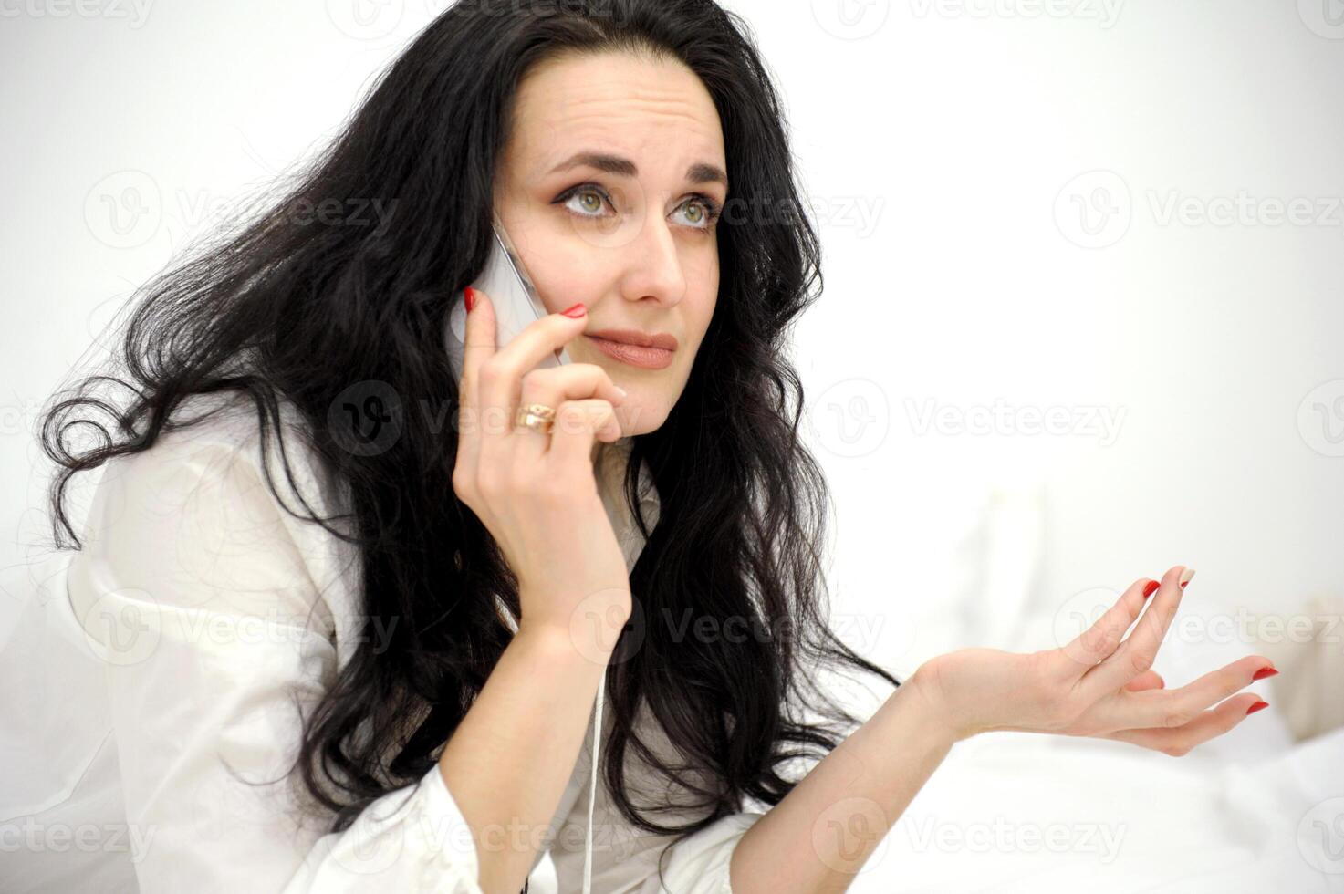 woman's face close-up in hands of phone unpleasant conversation emotionally raised eyes twisted lips on white background place for text unsuccessful order of discontent raise eyebrows wrinkle forehead photo
