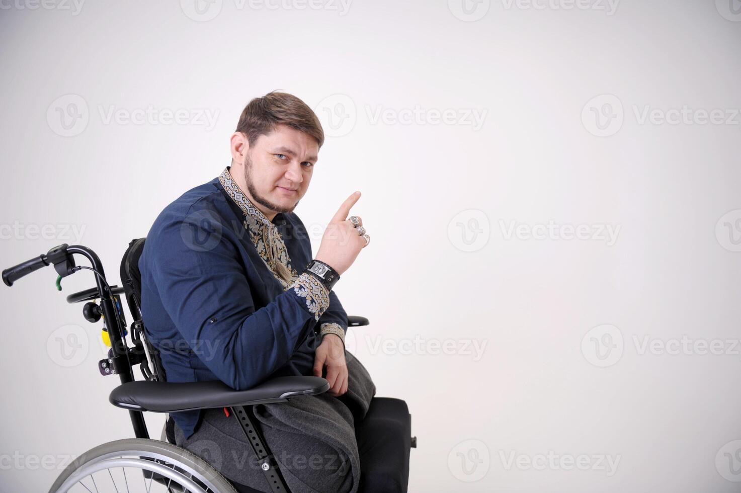 The man raised his finger up pointing to the empty disabled man is sitting in a wheelchair. He holds his hands on the wheel. Nearby are his colleagues photo