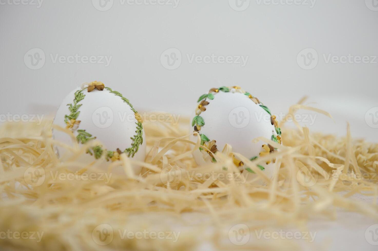 Easter eggs are decorated in variety of ways using an ordinary needle souvenir miniature drill Easter from place for text is handmade 2 eggs in white sawdust with green yellow ribbon embroidery photo