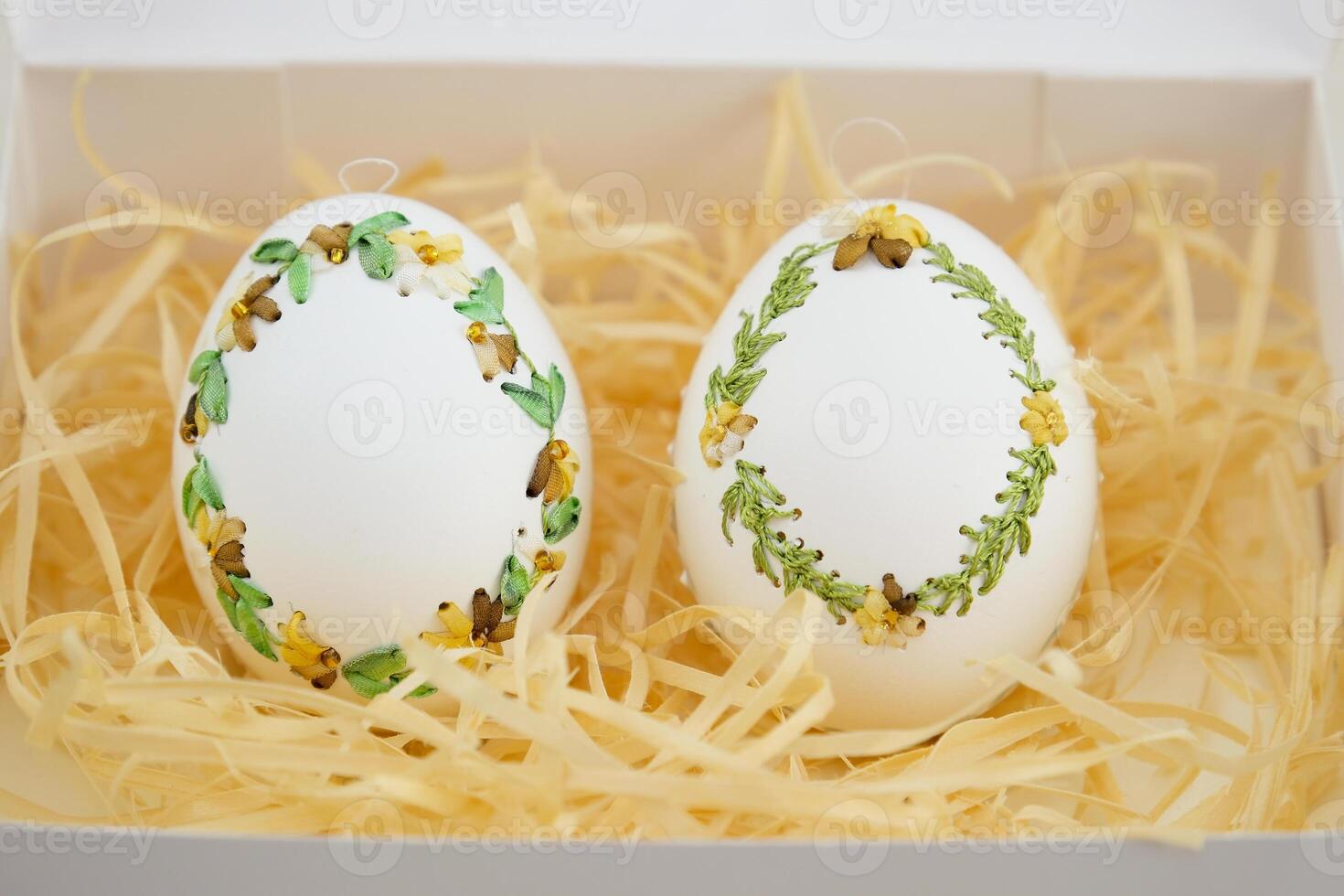Easter eggs are decorated in variety of ways using an ordinary needle souvenir miniature drill Easter from place for text is handmade 2 eggs in white sawdust with green yellow ribbon embroidery photo