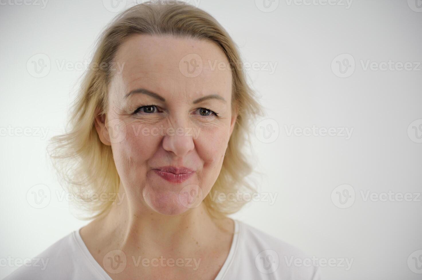Studio shot of beautiful young woman with blonde hair and naked shoulders. Girl squeeze or blow lips on gray background with copy space for your text or advertising content photo