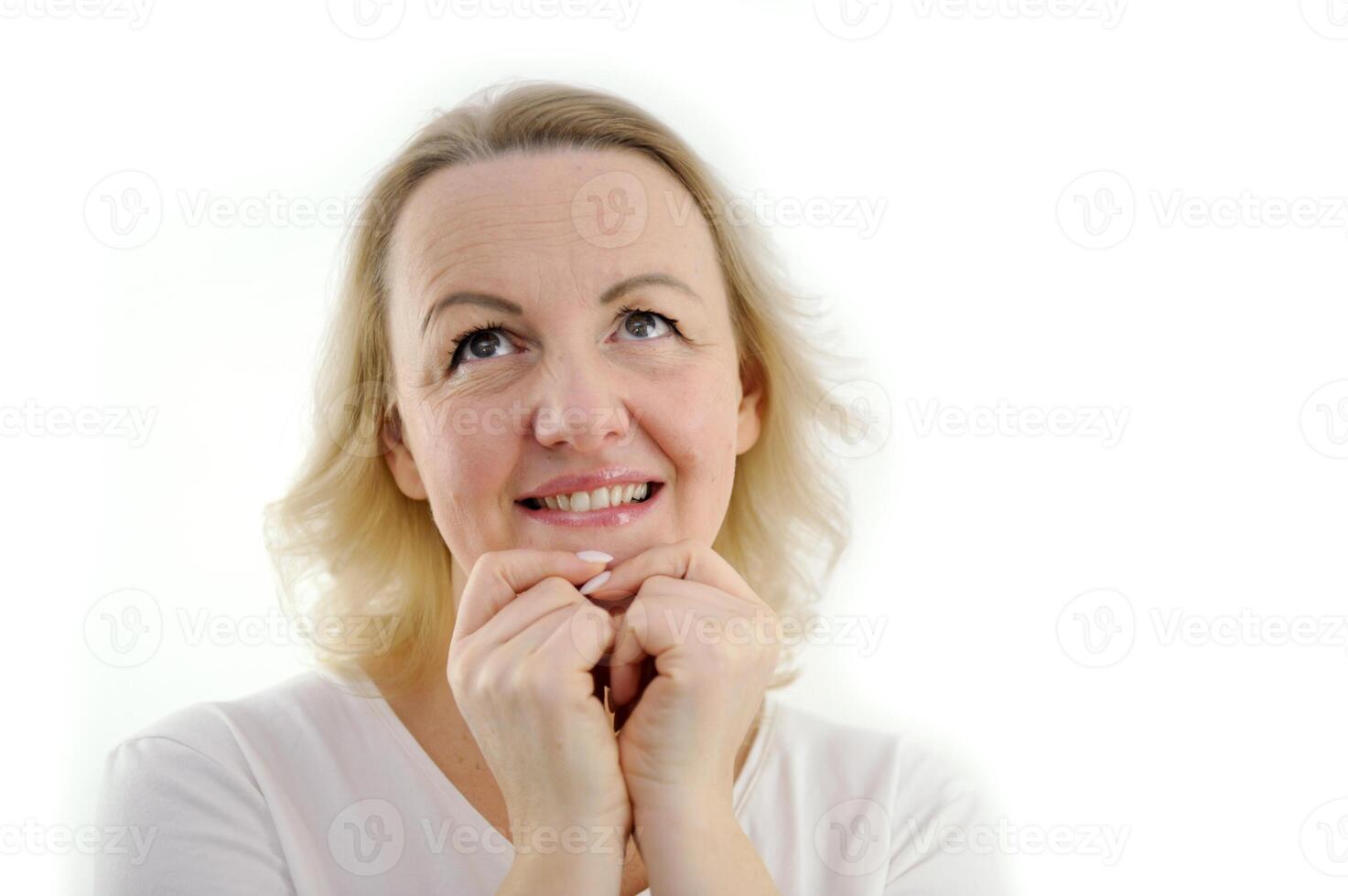 beautiful middle-aged woman is waiting for gift for holiday she folded hands near face expectation tenderness beauty on white background place for text buy sale advertising excellent service photo