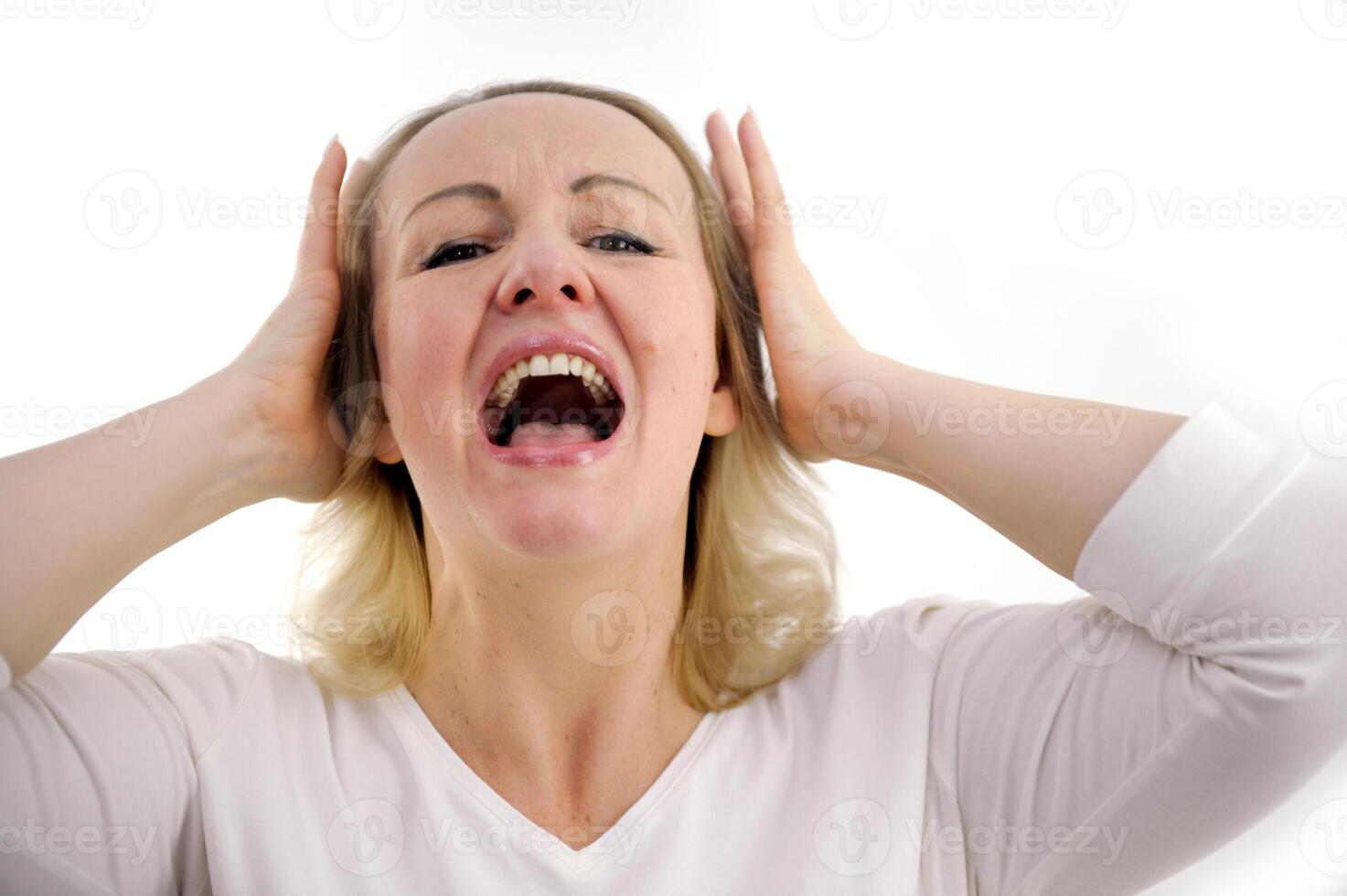 I do not want to hear it Closeup portrait of upset, tired woman screaming loud close eyes embracing her had by hands isolated on gray background photo