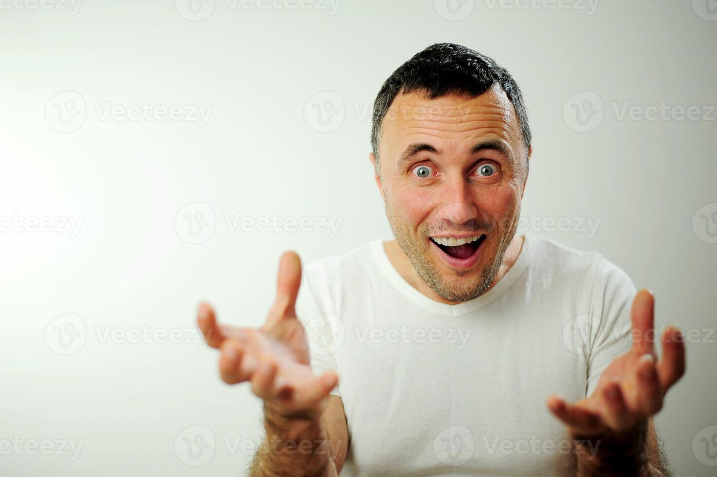 Handsome adult man opened his arms and laughs in the frame success victory joy Medical product advertisement The man does not shave White background white t-shirt Beautiful smile with white teeth photo