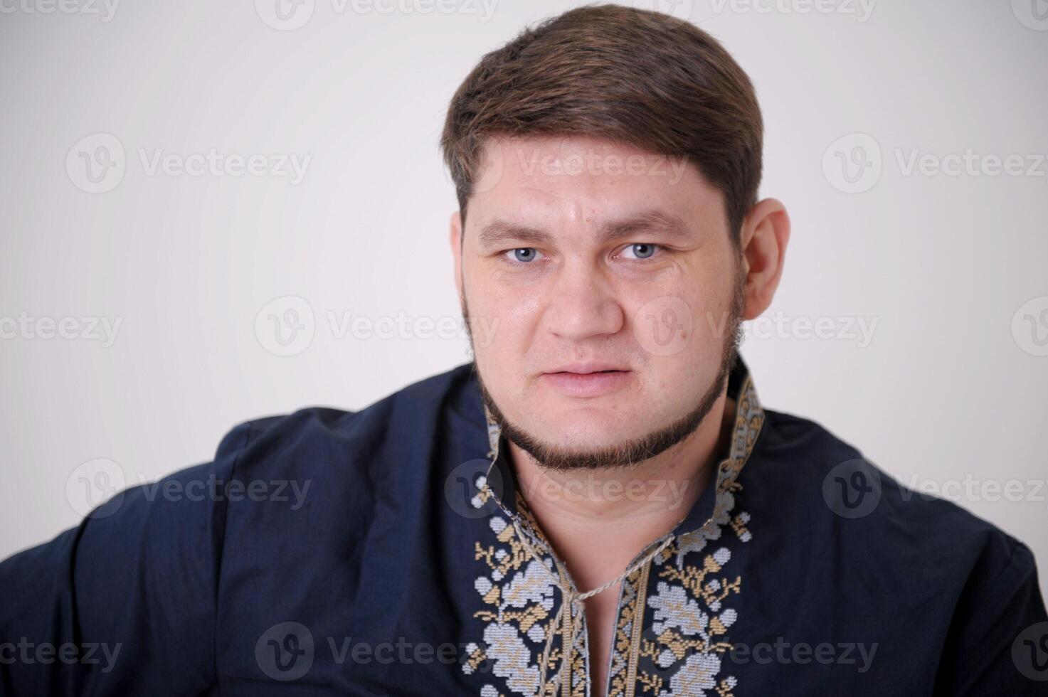 Waist-up shot of serious-looking unemotional good-looking adult man in gray t-shirt looking at camera calm and strict, being snob and hard to impress standing over gray background. photo