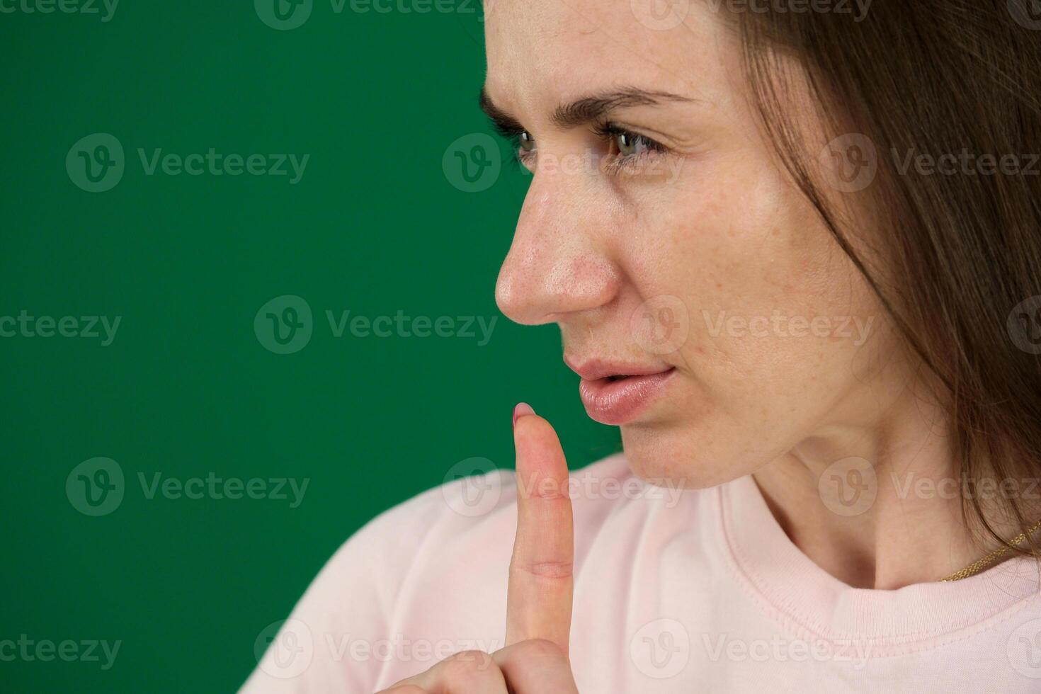 Young girl making silence gesture on green background different emotions of a young girl on a green background chromakey beautiful facial features real people pink T-shirt white skinned. European photo