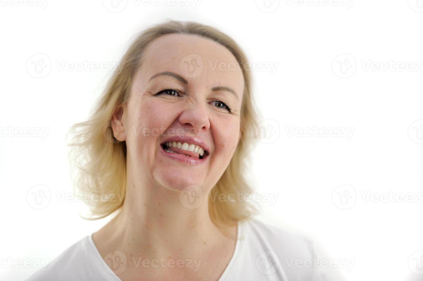 sincere smile of a beautiful woman glowing eyes close-up face on a white background teeth ajar tongue is visible joy tenderness female beauty tenderness charm middle age blond hair photo