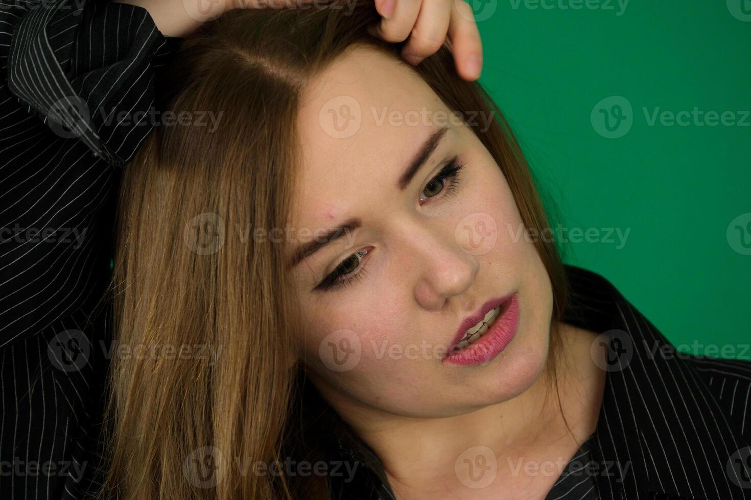 Portrait of the young girl with horns woman on a green background chromakey in a black striped mens shirt different emotions facial expression close-up advertising space for text clean. kind eyes photo