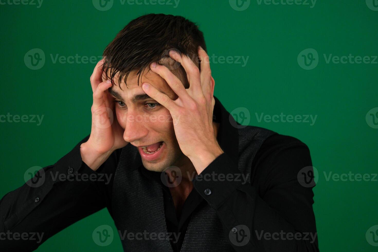Portrait of a young man screaming out loud against emotions of a handsome man guy on a green background chromakey close-up dark hair young man photo