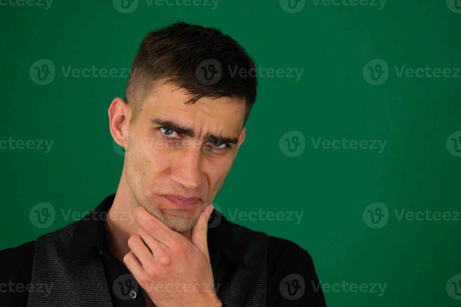 Close-up image of a handsome male teenager isolated emotions of a handsome man guy on a green background chromakey close-up dark hair young man photo