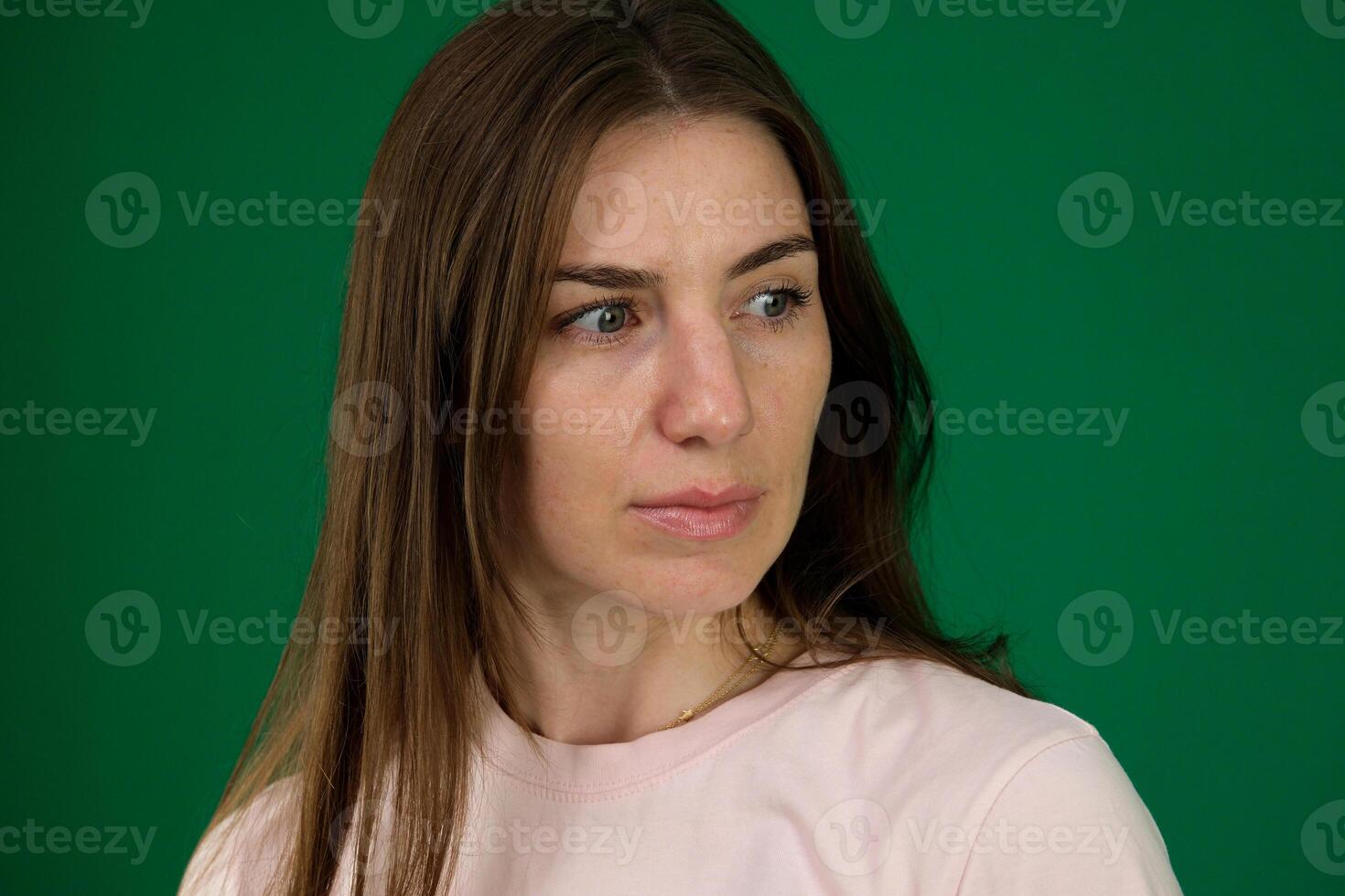 Attractive brunette woman wondering and looking up with long hair over shoulder different emotions of a young girl on a green background chromakey beautiful facial features real people photo