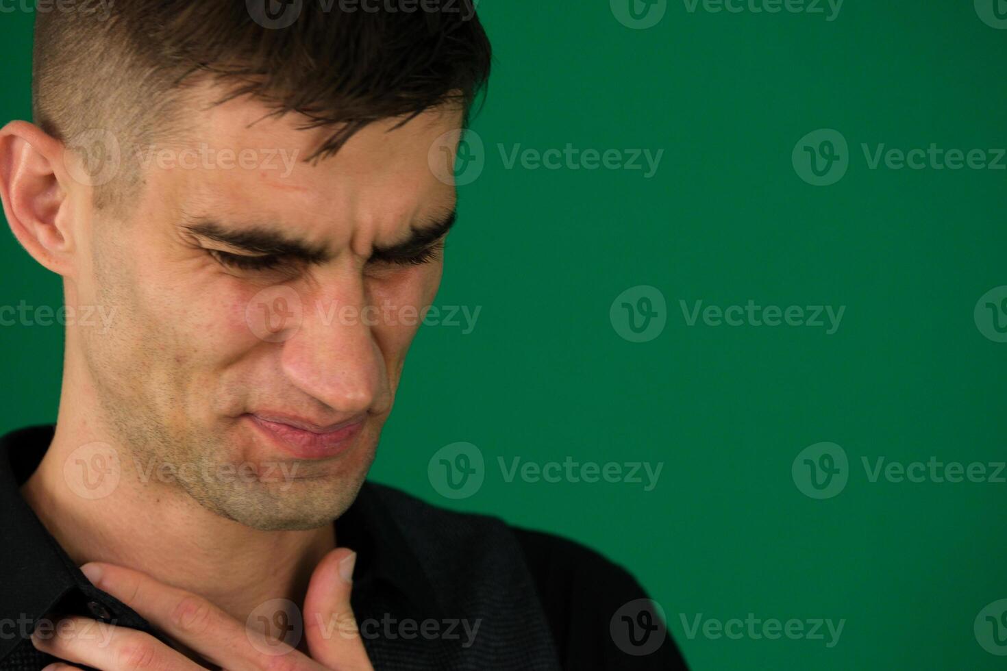 Men are showing chest pain. Close-up portrait of a funny crying man emotions of a handsome man guy on a green background chromakey close-up dark hair young man photo