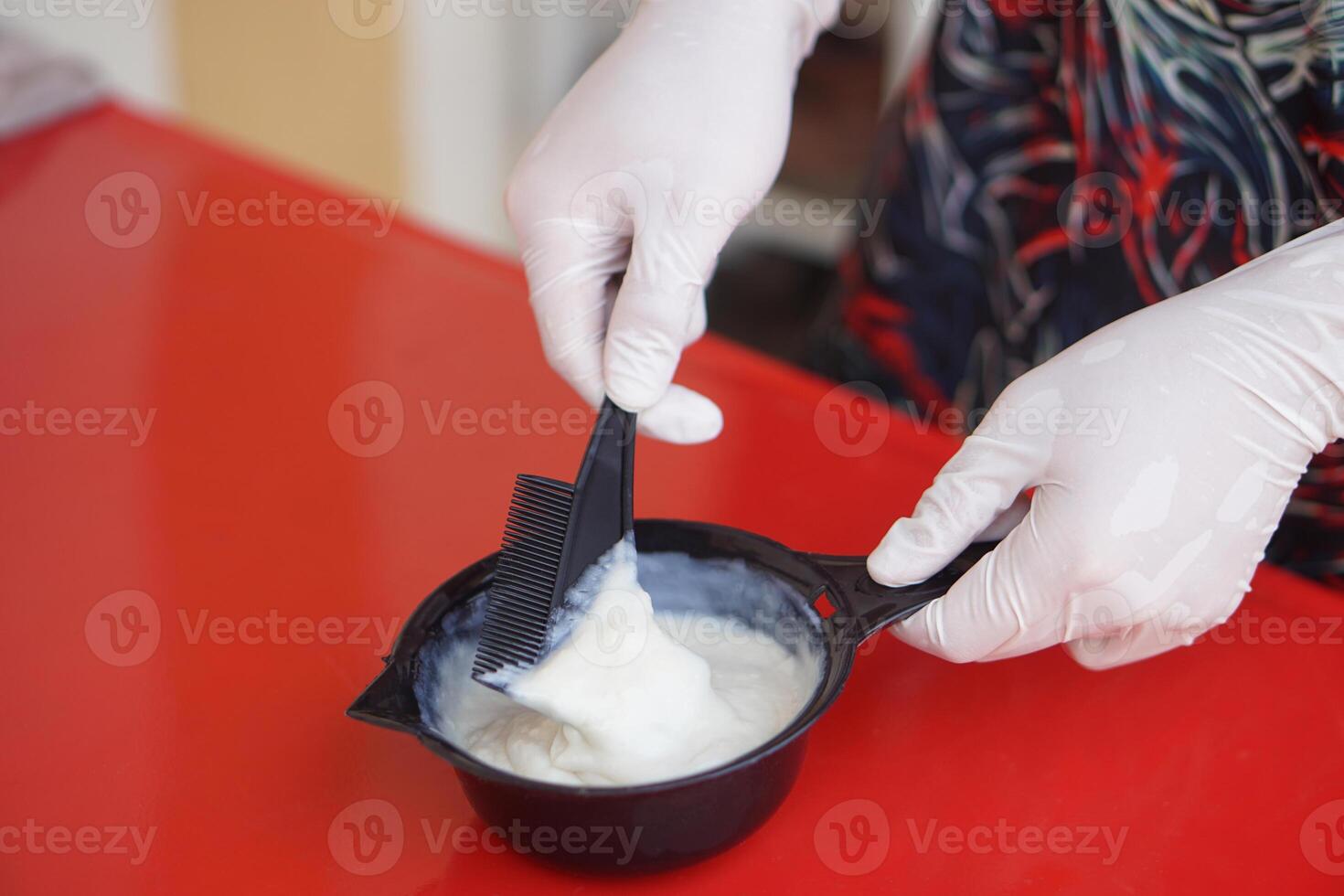 Close up hands wears gloves, mixing dye hair color cream in black bowl before dying client's hair. Concept, hair beauty product for changing hair color by professional hairdresser. photo