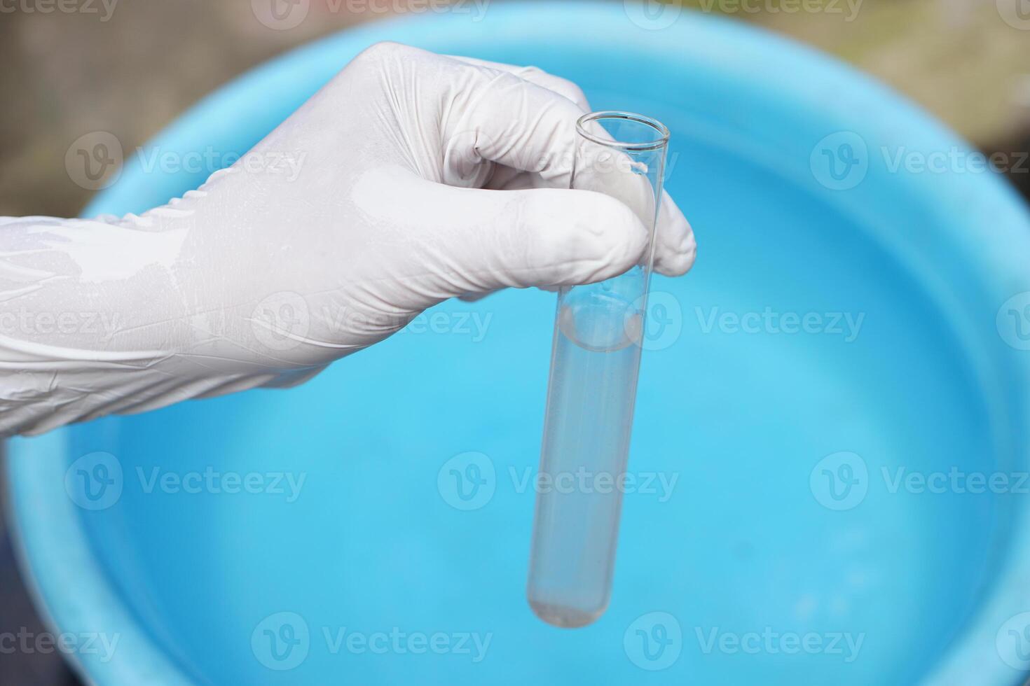Close up ecologist hand wears glove holds test tube of water. Concept, Inspecting water quality from nature source that use in daily life. Examination water pollution. Environmental problems. photo