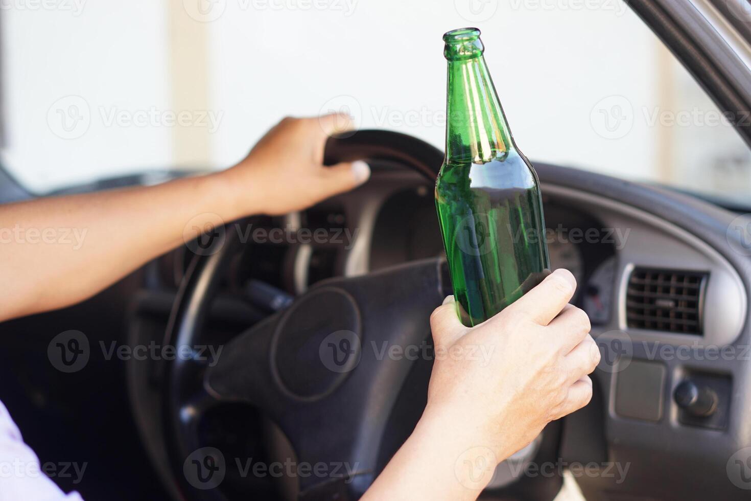 Close up a driver holds bottle of beer in car. Concept , Campaign for don't drive, don't drink alcohol that can cause car accident and illegal. Dangerous driving when drunk. photo