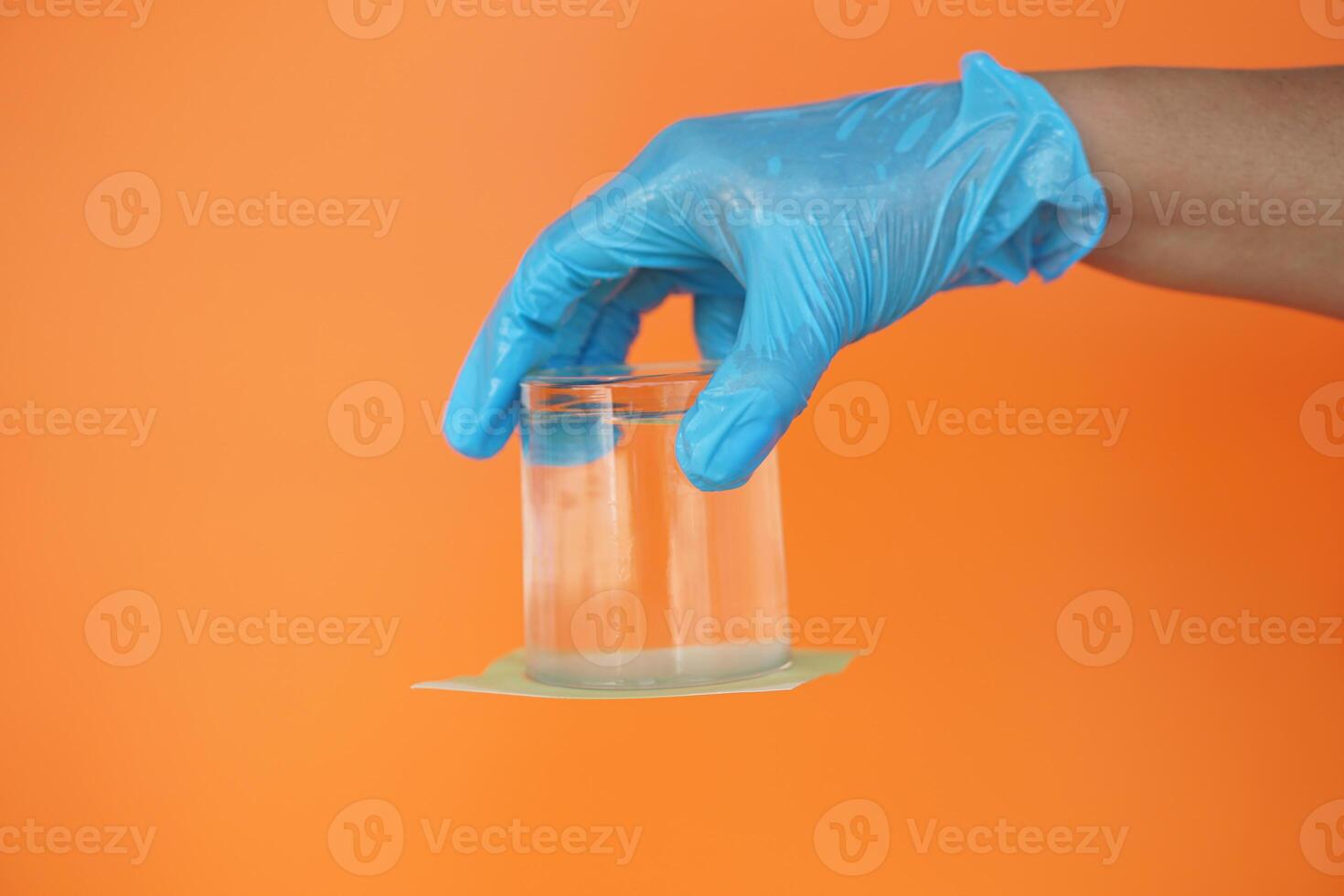 Closeup hand hold and turn a glass of water over down. covered the glass with paper. Concept, science experiment about air and liquid pressure. Easy science subject activity, education. photo