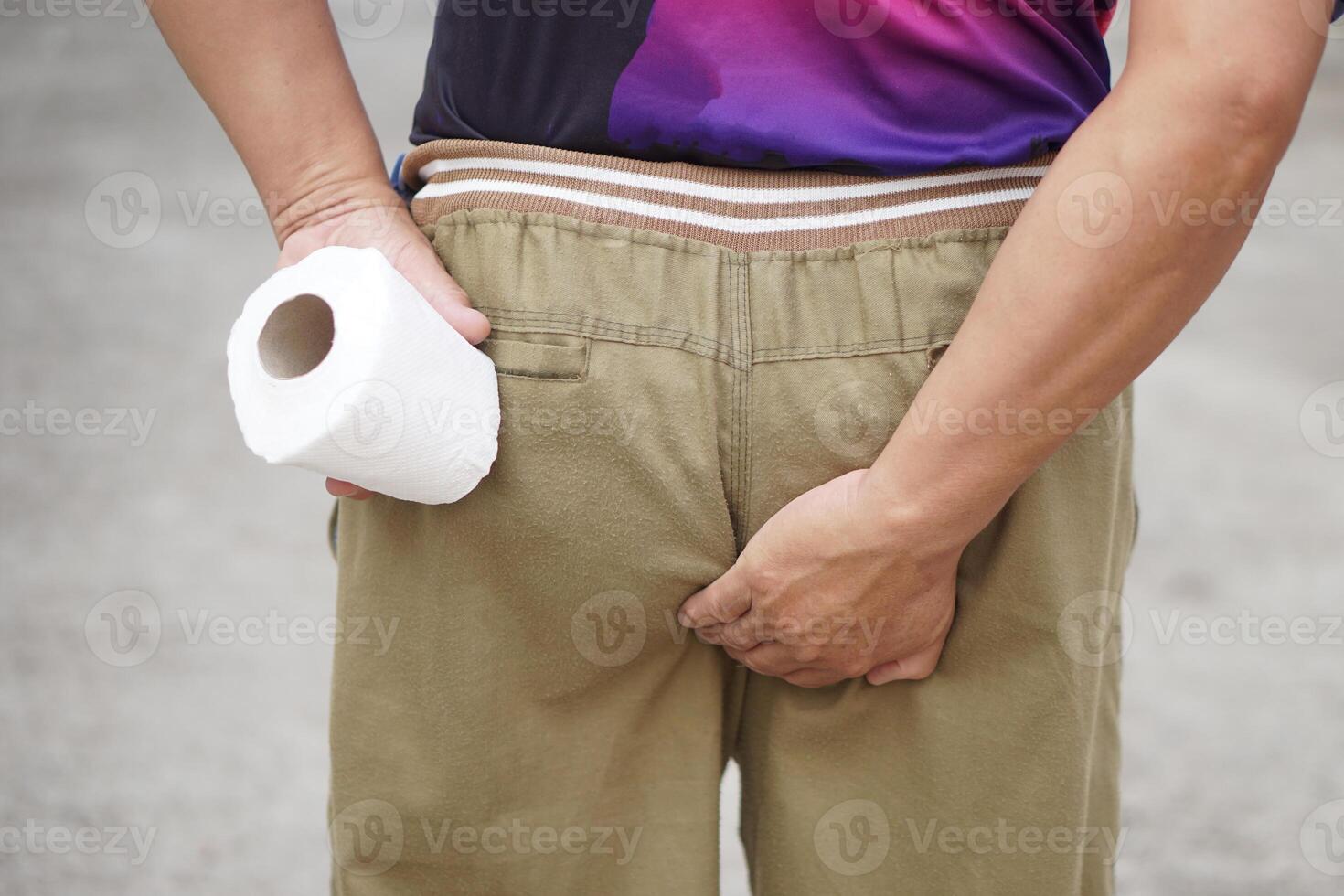 Close up man holds tissue paper roll and hand touch his bottom. Concept, need to go to toilet. Diarrhea. Hemorrhoids. Health problems and health care. photo
