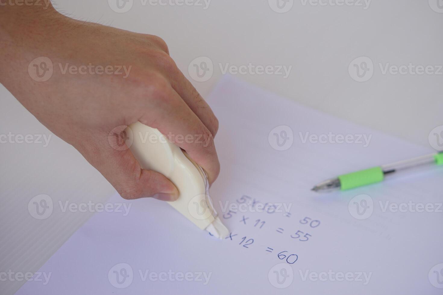 Close up hand use correction tape to erase mistake numbers on paper. Concept, education equipment for delete incorrect writing on paper. Easy and convenient to use. School supplies or office tool photo