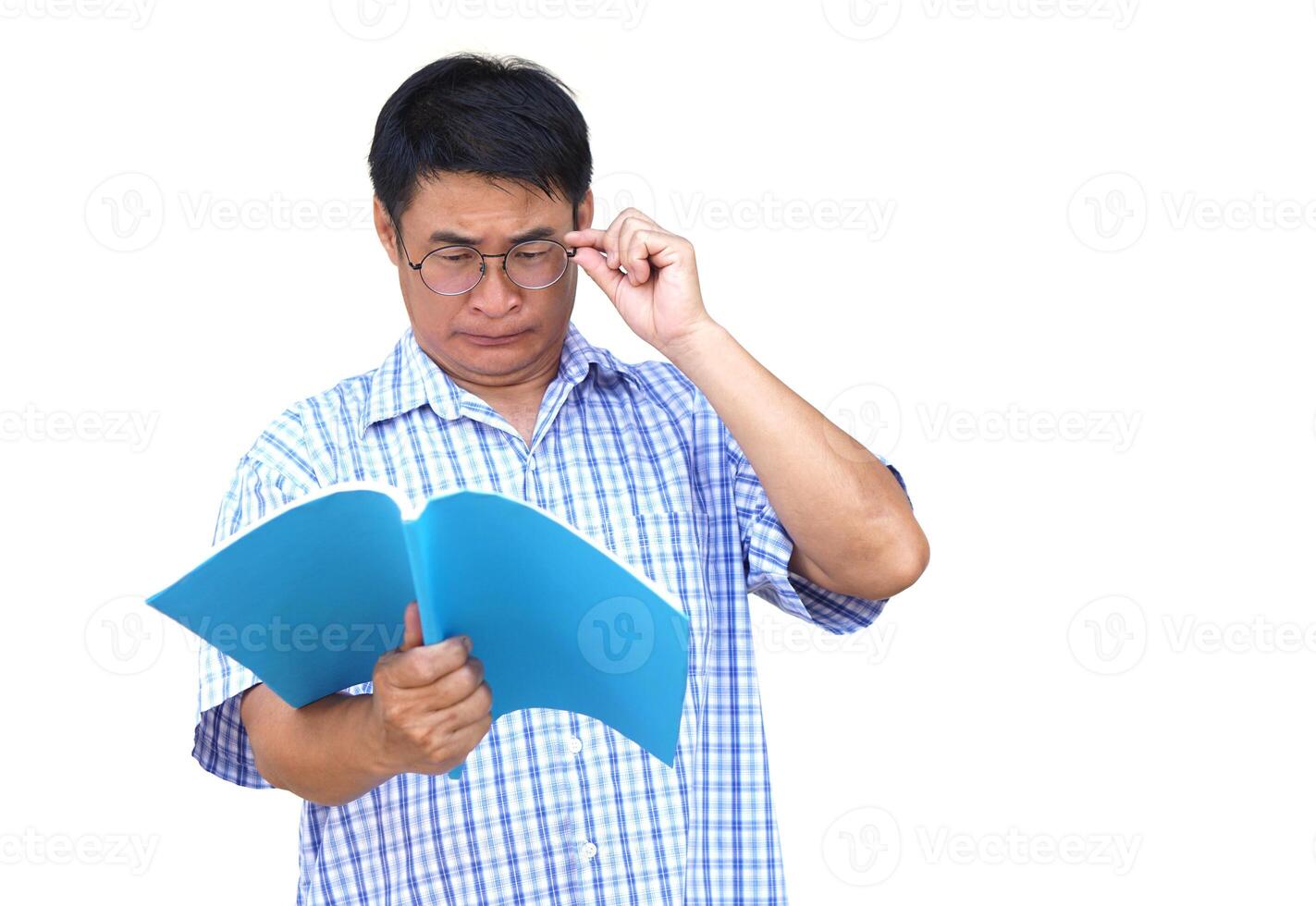 Asian middle aged man wears eyeglasses, tries to read book. White background. Concept , Eyesight health problem. Optometry. Glasses with convex or concave lenses. Myopia.Eye disease. photo
