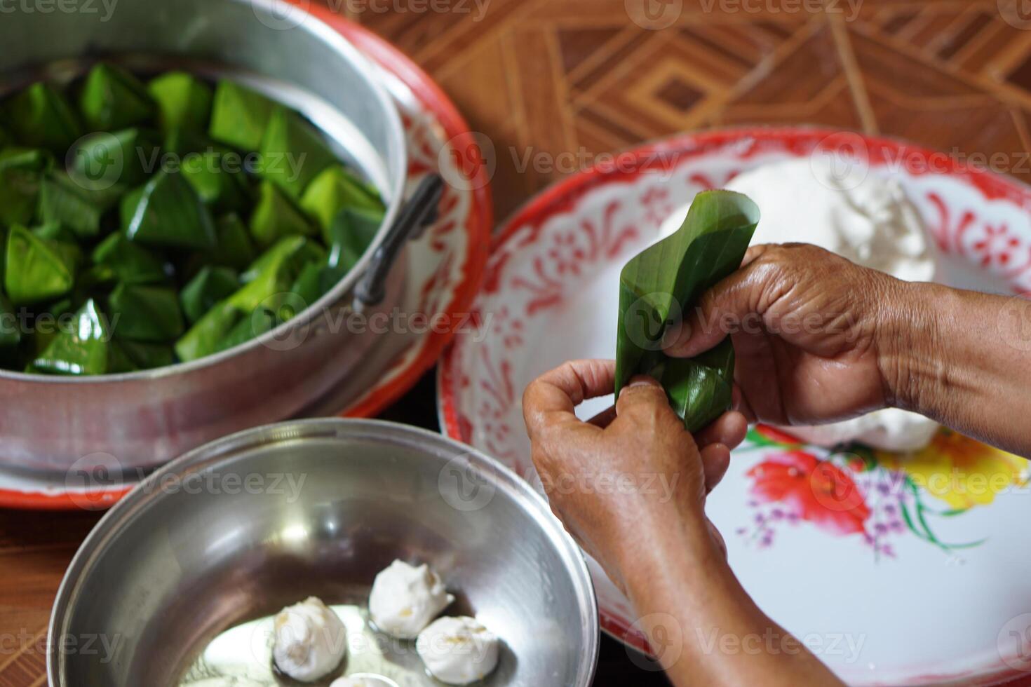 Close up hands hold banana leaf to wrap dough bun for cooking Thai traditional dessert. Concept, Thai food. How to cook, step of cooking. Thai lifestyle, Prepare food for cultural celebration events. photo