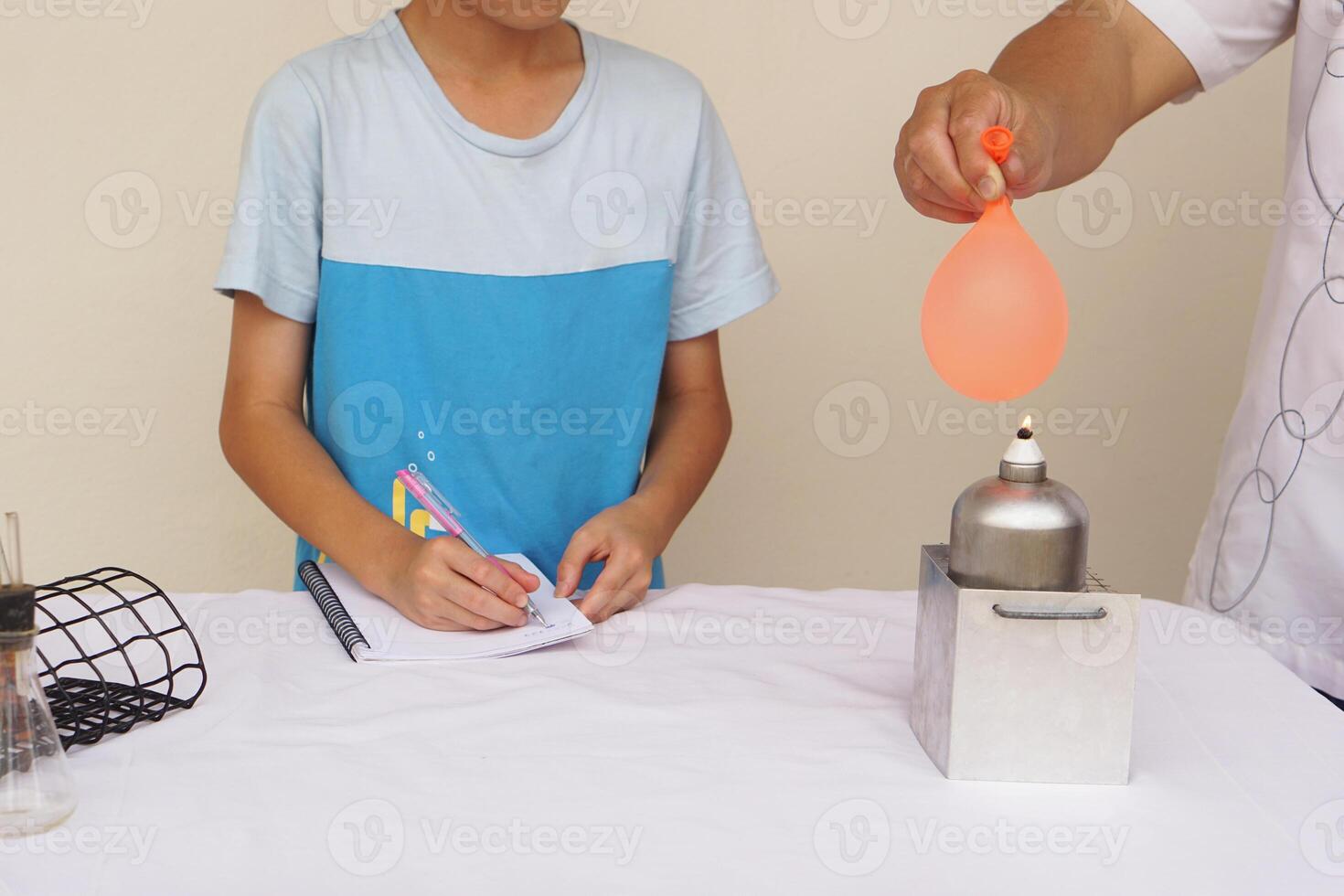 Unidentified boy is studying about science experiment about balloon burning on fire. The expanding of air pressure , reaction of chemical substance. Concept, education. photo