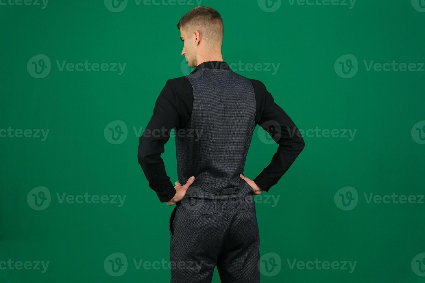 Man Standing Turned Back to Camera Full Lenght. Sport man Isolated emotions of a handsome man guy on a green background chromakey close-up dark hair young man photo