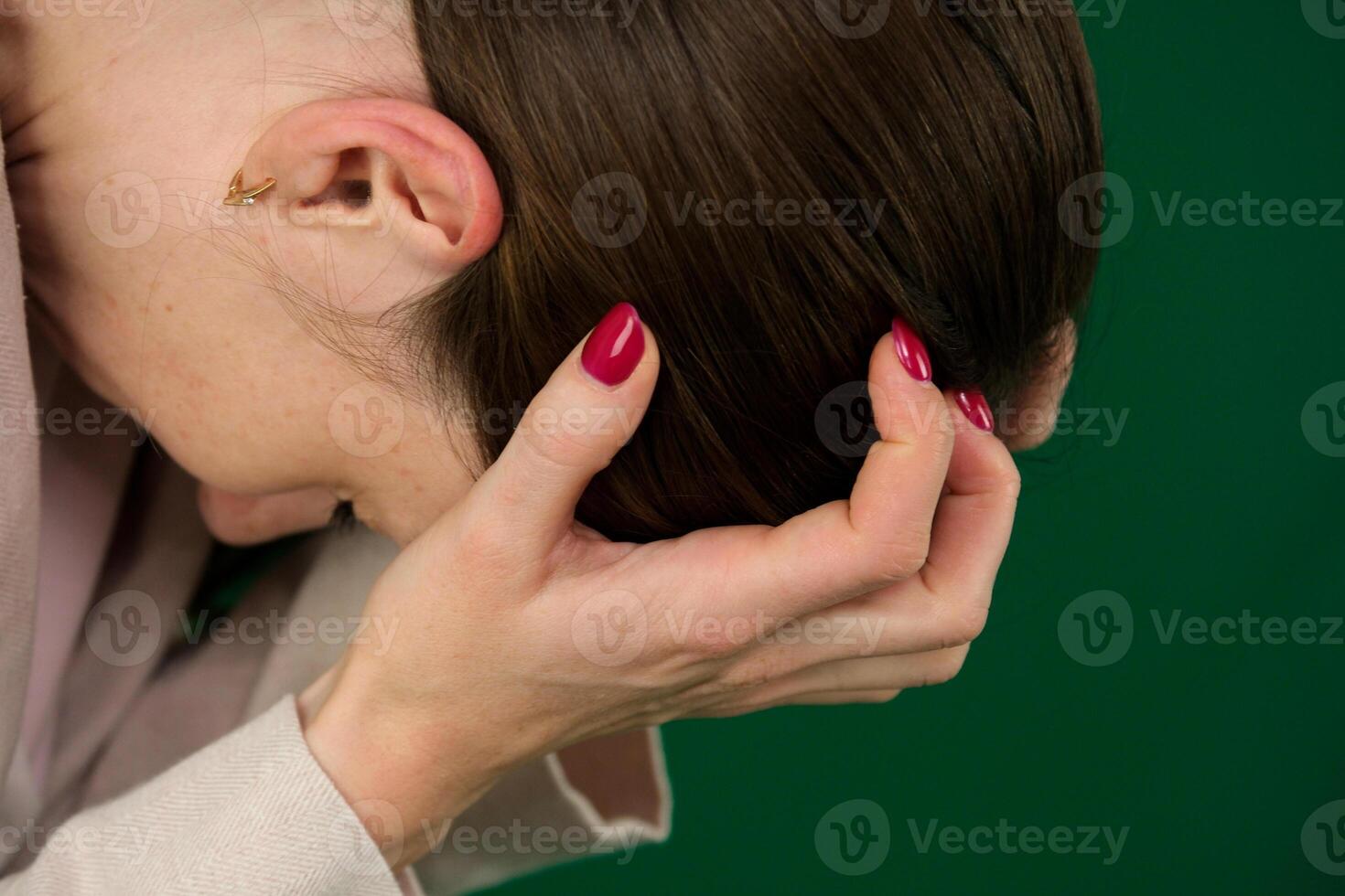 picture shows a young woman in an emotional outcry on a green background, chromakey, close-up of a woman with emotions in a beige jacket, red manicure, blue eyes photo