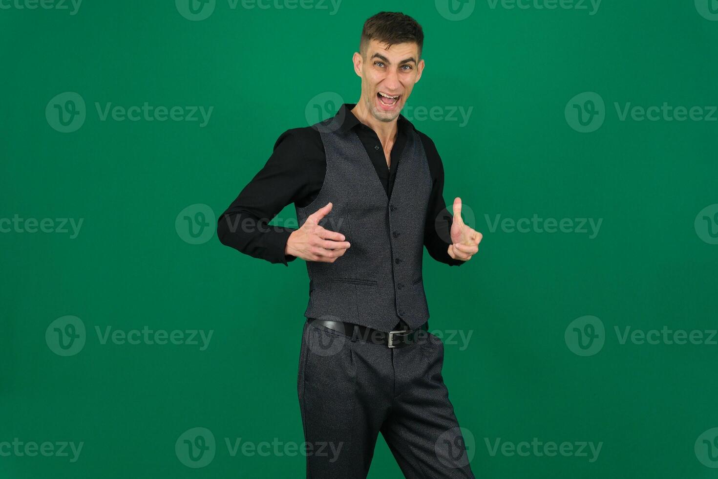 Handsome man doing different expressions in different sets of clothes emotions of a handsome man guy on a green background chromakey close-up dark hair young man photo