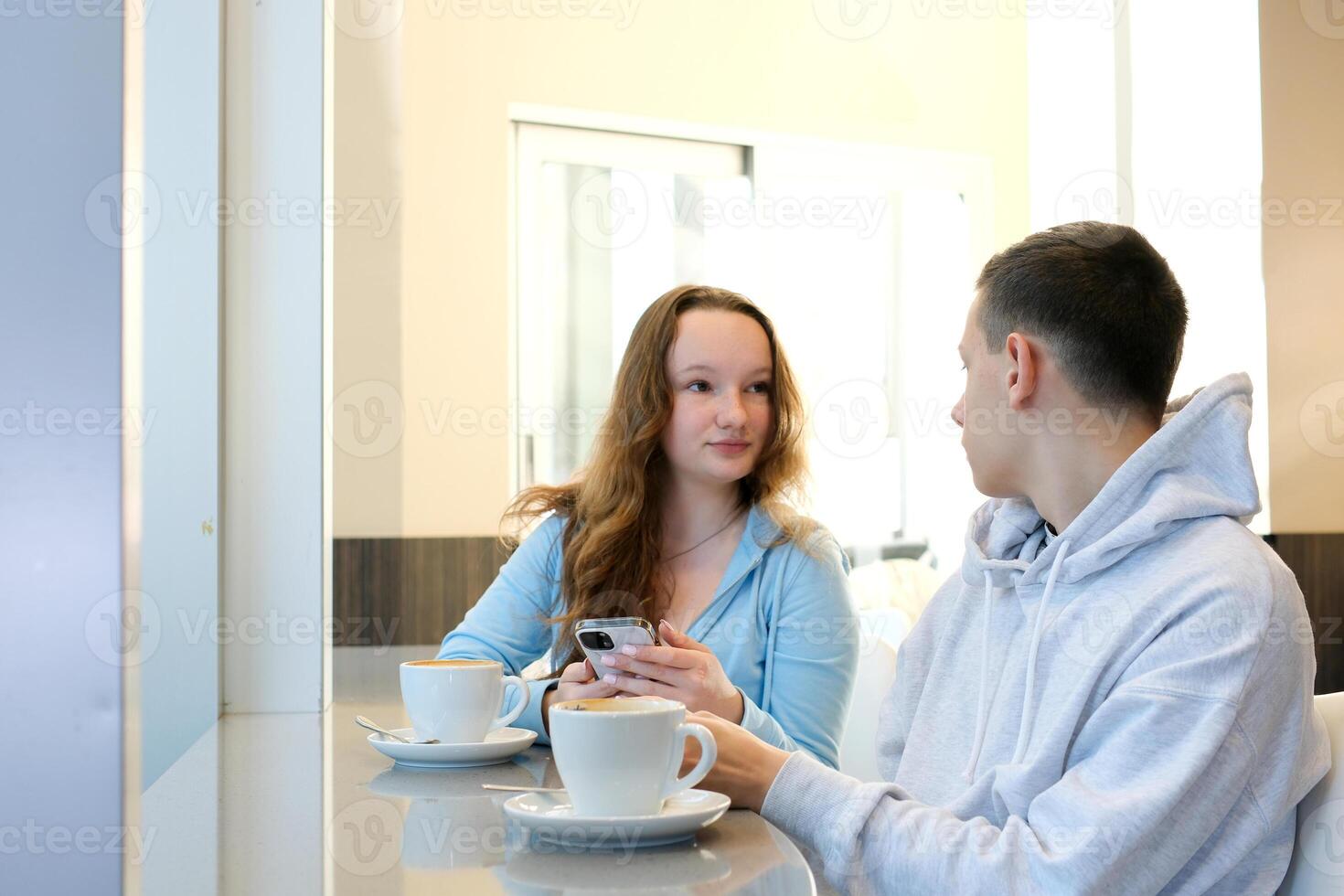 Young couple sitting at cafe and using mobile phone Cheerful man and woman are sitting in cafe dating chat rest photo