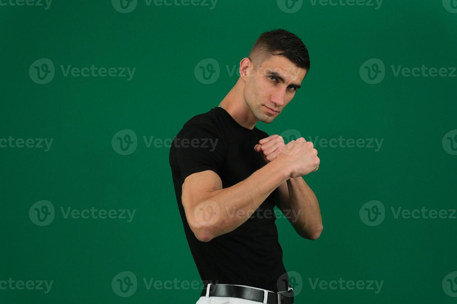 Young man fighter posing over emotions of a handsome man guy on a green background chromakey close-up dark hair young man photo