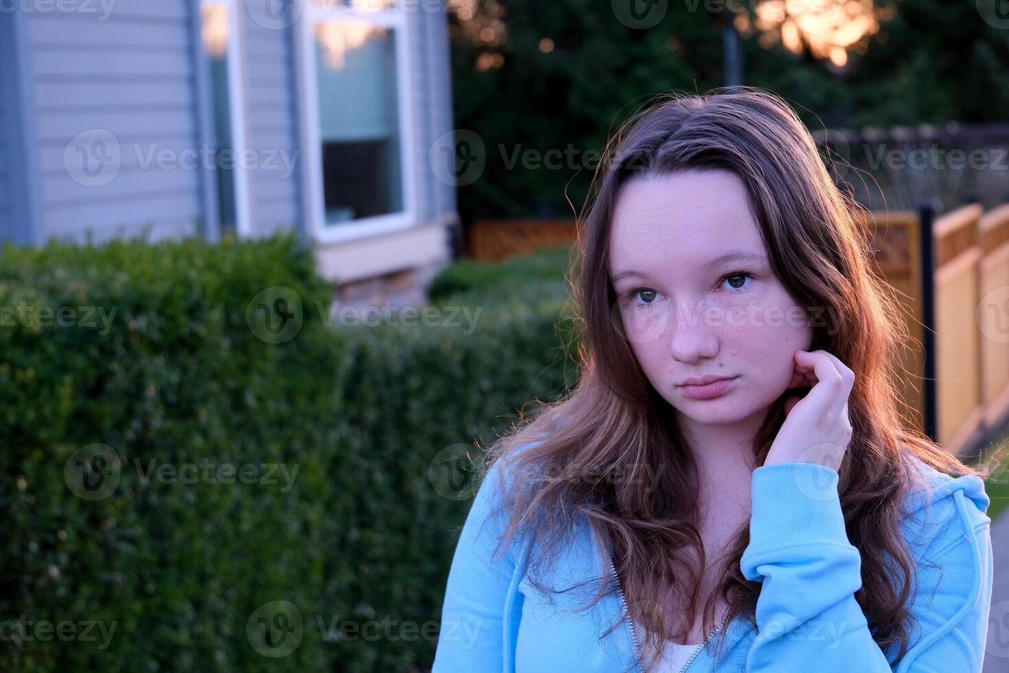 face of beautiful young girl looking at phone turn head look into camera close-up tenderness modesty purity beauty virginity straighten hair embarrassment sincerity in the eyes of adolescence teenager photo