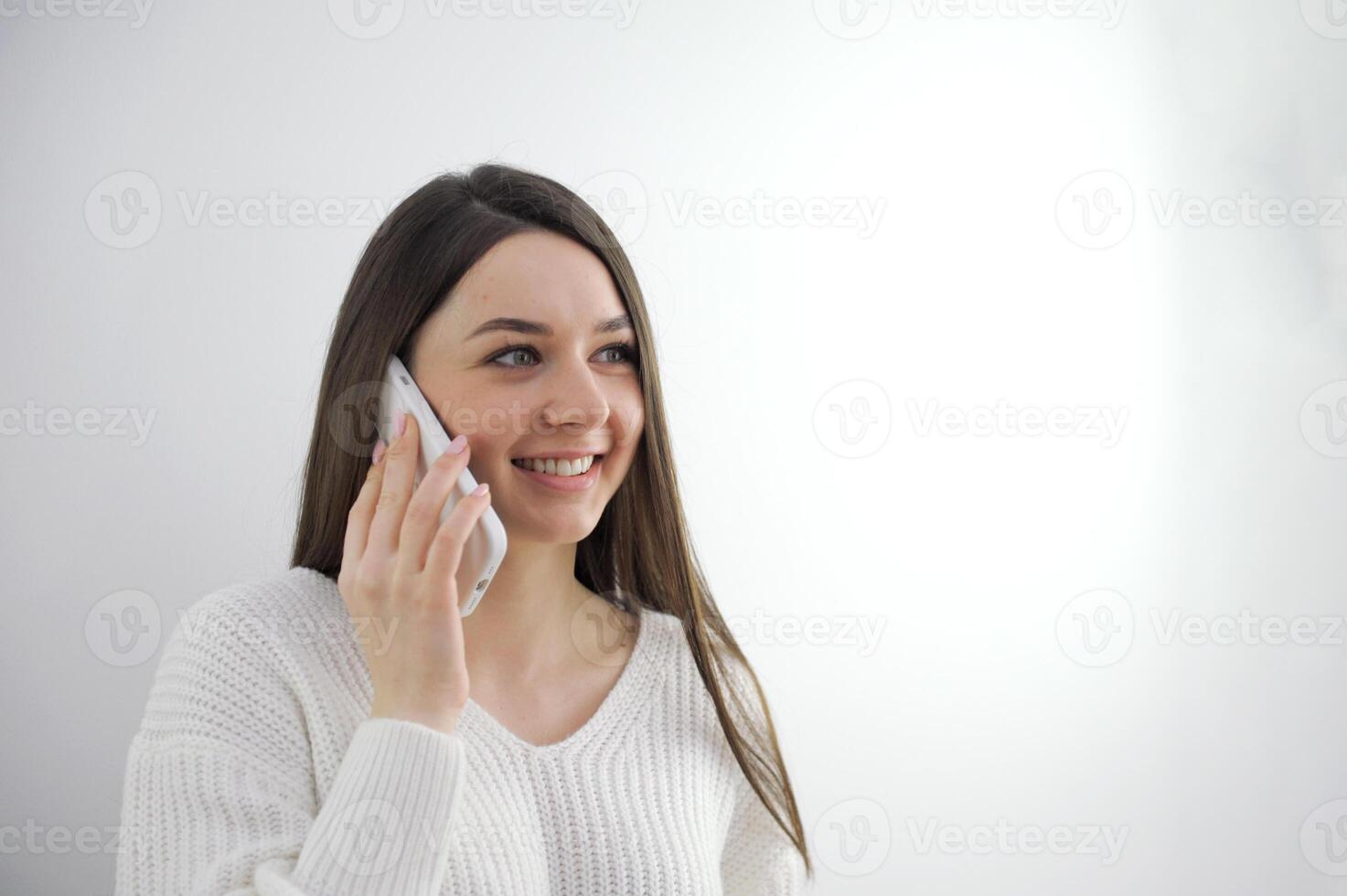 Excited amazed charming brunette woman talking on mobile phone, isolated over gray background. Girl with mobile cell phone. photo