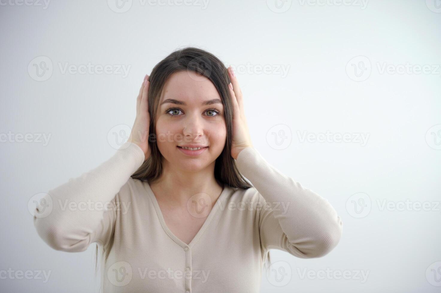 the girl is surprised she holds two hands on her head look into the frame with her hands up young young woman on a white background beautiful face youth freshness smile photo