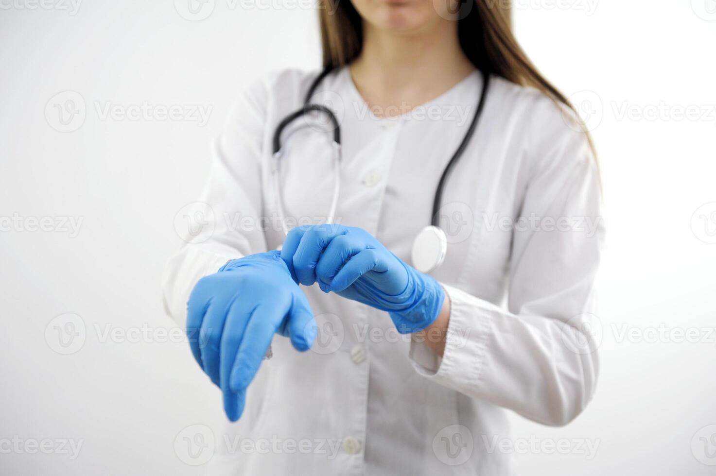 White man who's doctor wears blue medical gloves on his hands. Studio photo on gray background. Horizontal.
