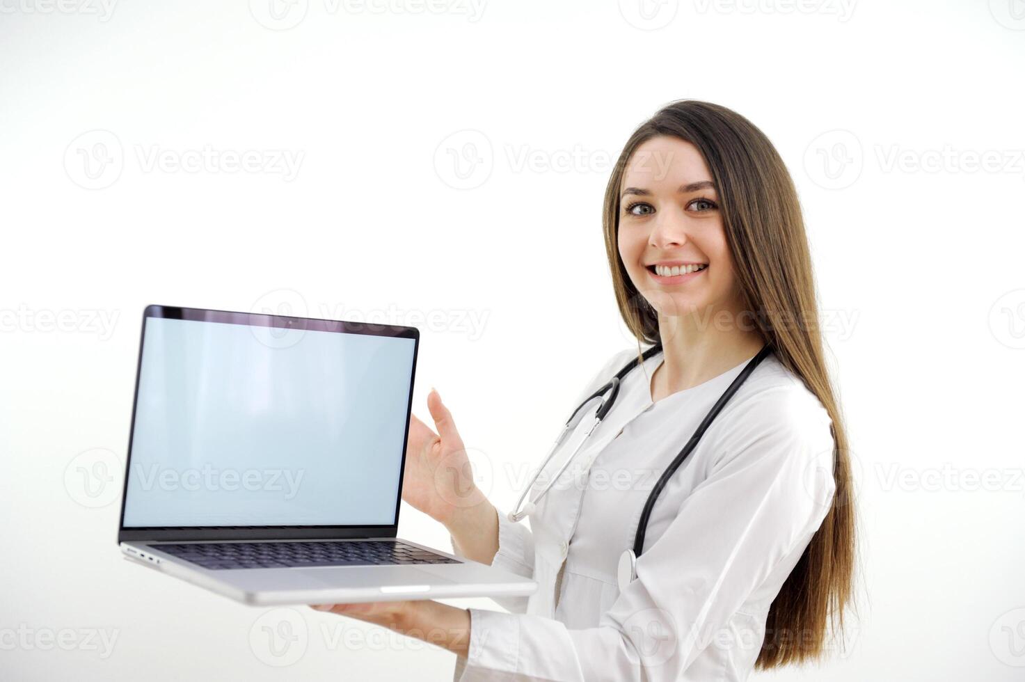beautiful young nurse holding laptop with white screen in hands smiling white background studio space for text ad trademark before meals slimming drugs long hair white teeth medical instruments photo