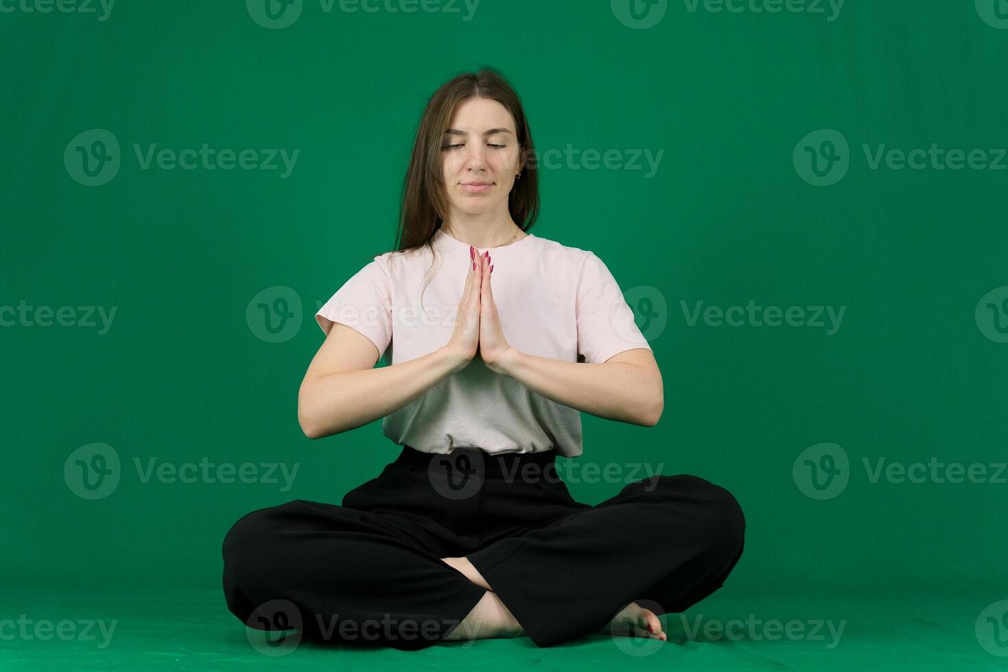 Yoga. Young girl goes in for sports. different emotions of a young girl on a green background chromakey beautiful facial features real people pink T-shirt white skinned. European photo