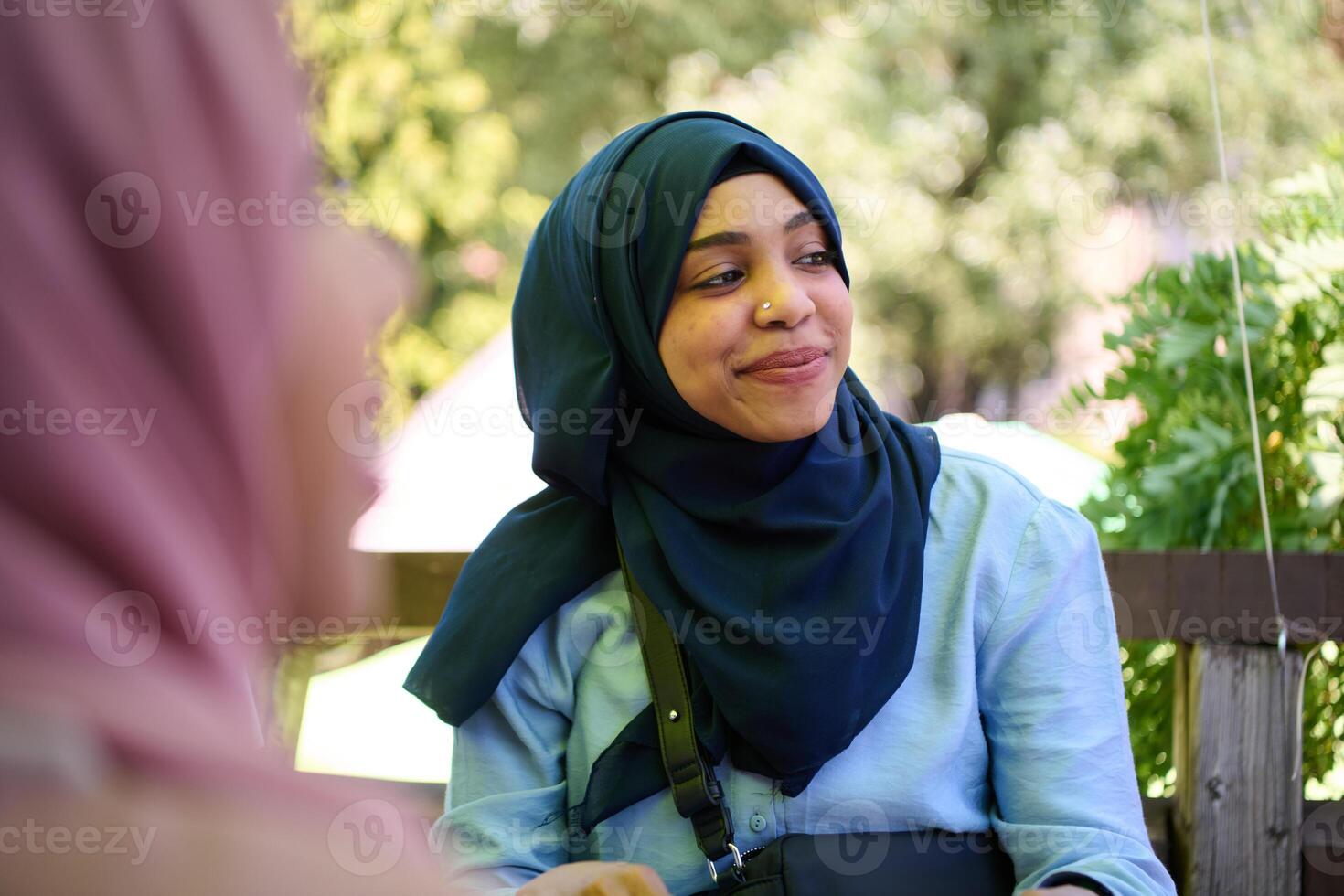 Middle Eastern Muslim Woman Enjoying Coffee and Conversation with Friend in Nature photo