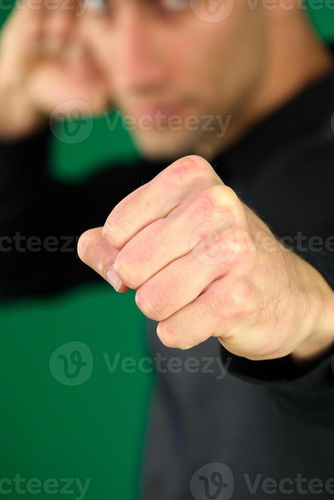Portrait of bearded man standing with boxing fists and ready to attack or defence, looking with angry face, looking at camera with aggression. Indoor studio shot isolated on blue background. photo