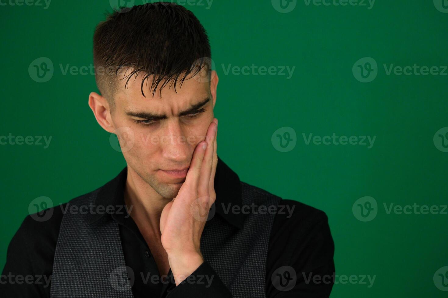 Tooth ache concept. Indoor shot of young male feeling pain, holding his cheek with hand, suffering from bad toothache, looking at camera with painful expression photo