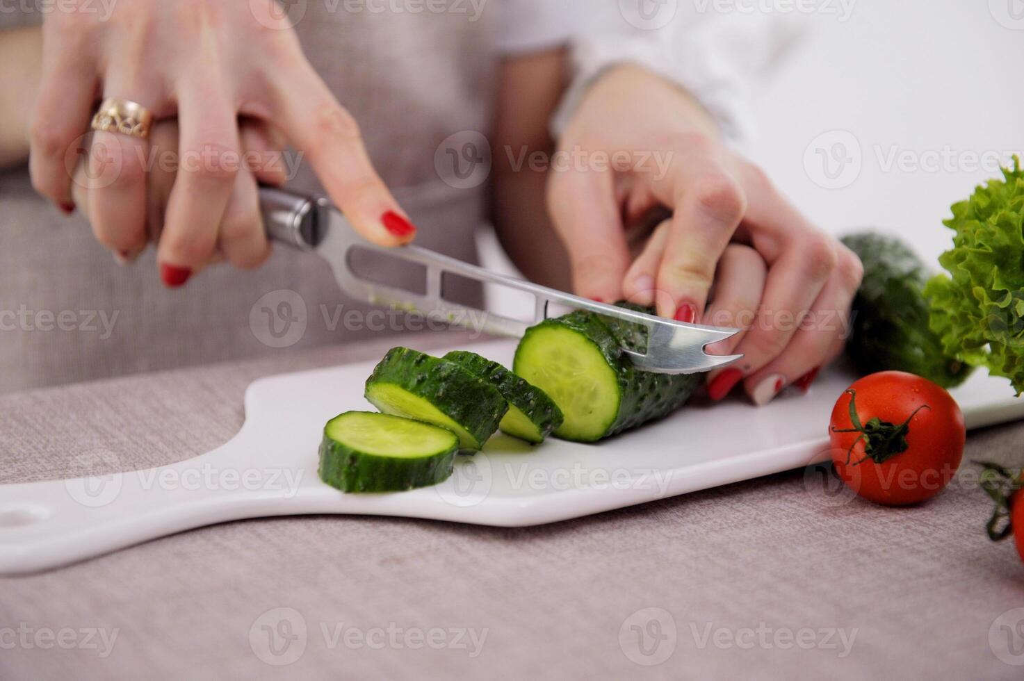 Loving mother teaches daughter to cook vegetable salad, little girl in apron holds knife cutting cucumber on wooden board mom look feel proud share family recipes and experience, pastime hobby concept photo