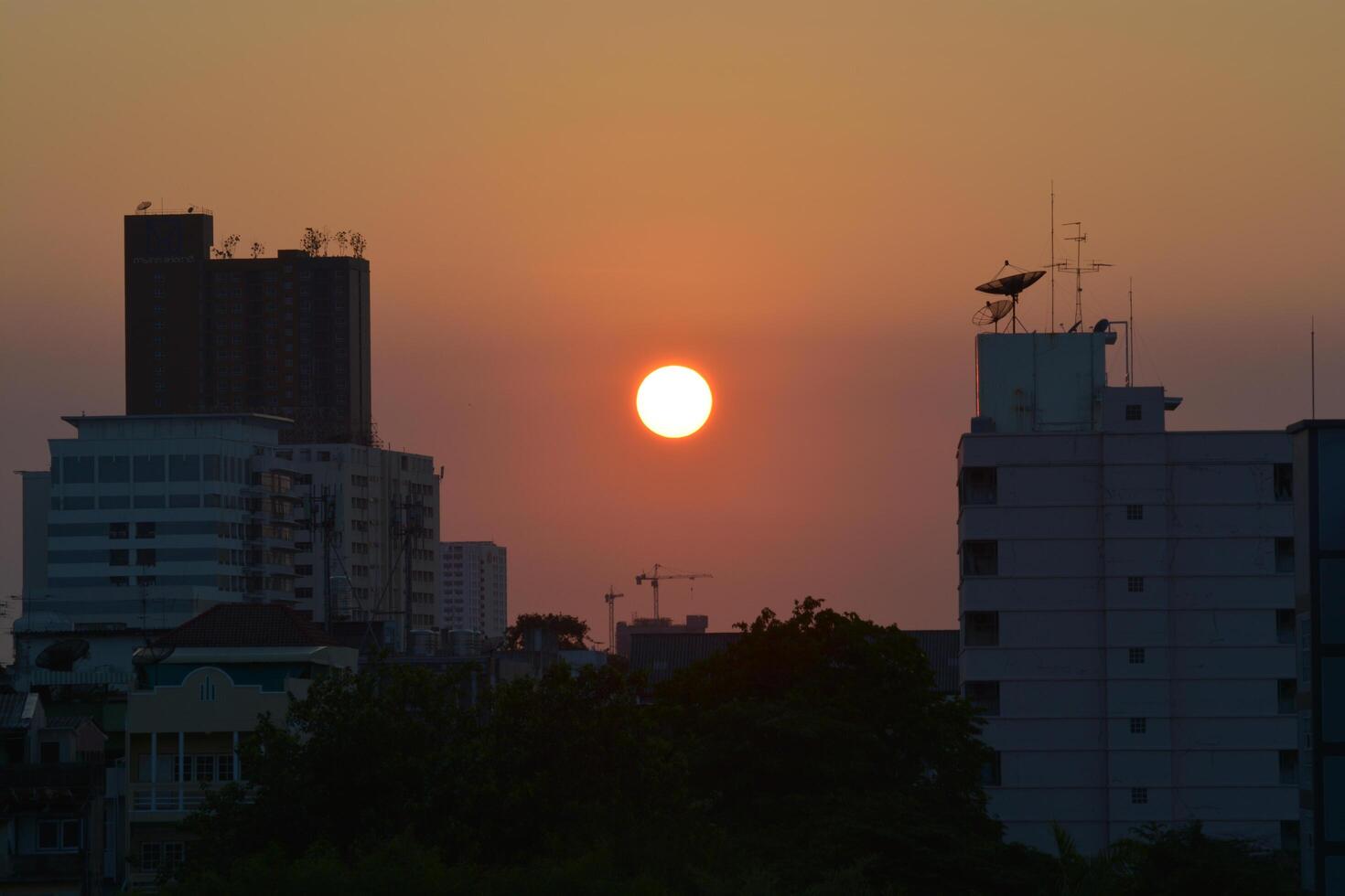 Bangkok, Thailand - April 28, 2024, A view of the sunset among tall buildings in a big city in the summer of Thailand. photo