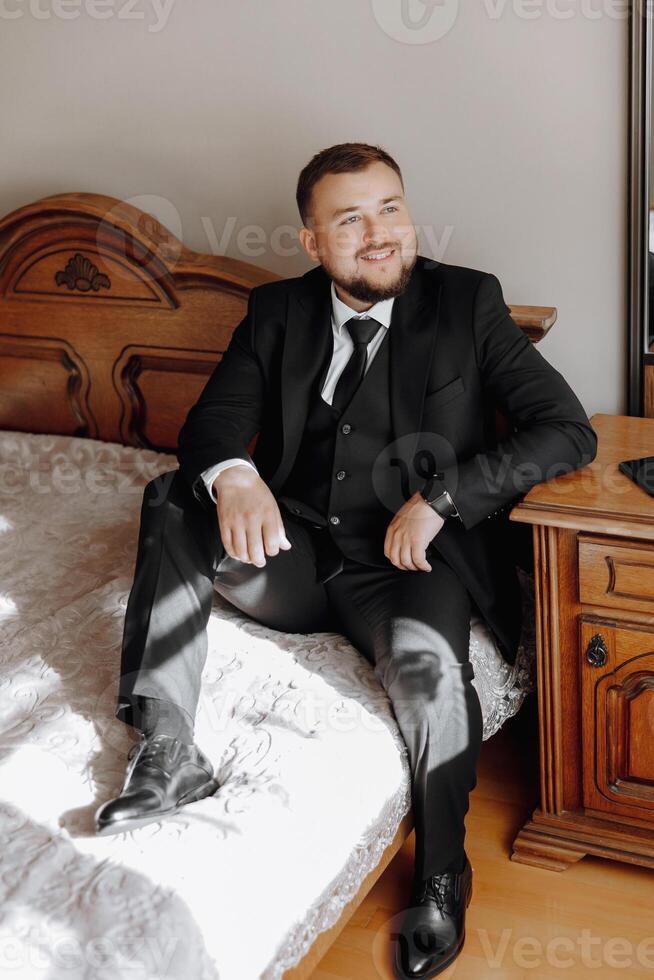 A man in a suit and tie is sitting on a bed photo