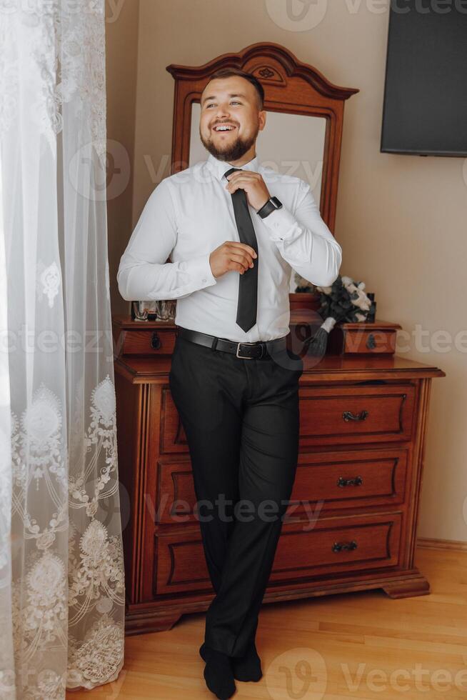 A man in a suit and tie stands in front of a dresser photo