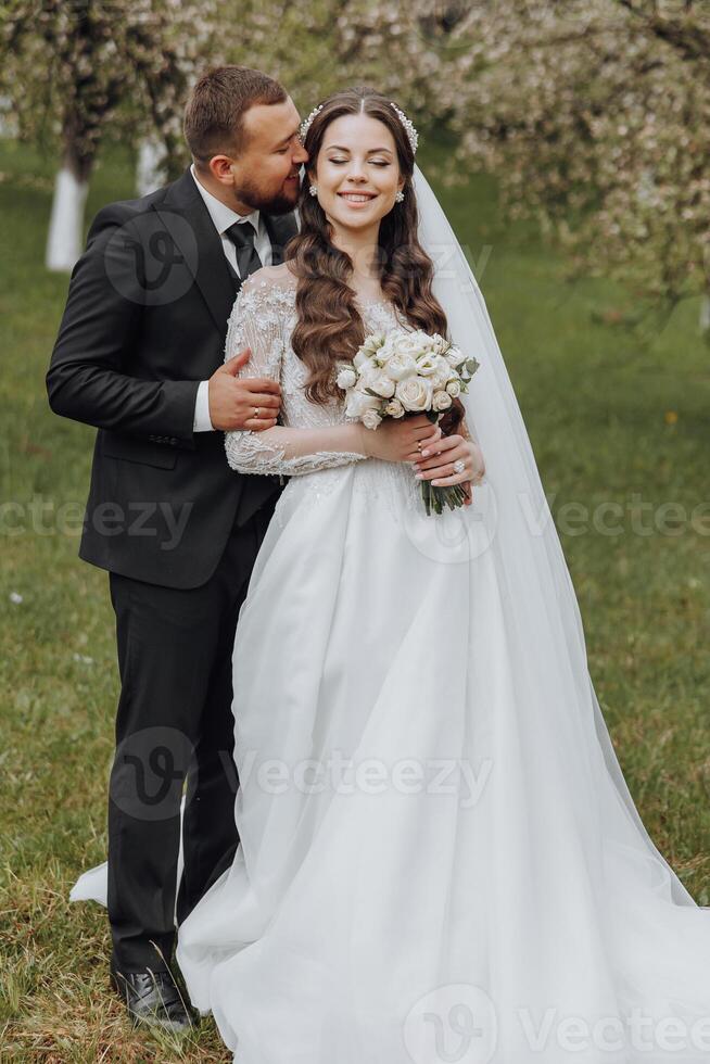 A bride and groom are posing for a picture in a field photo