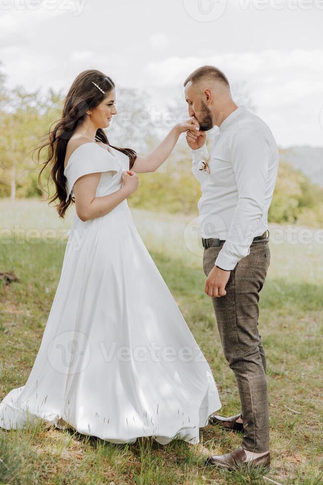 A bride and groom are standing in a field photo