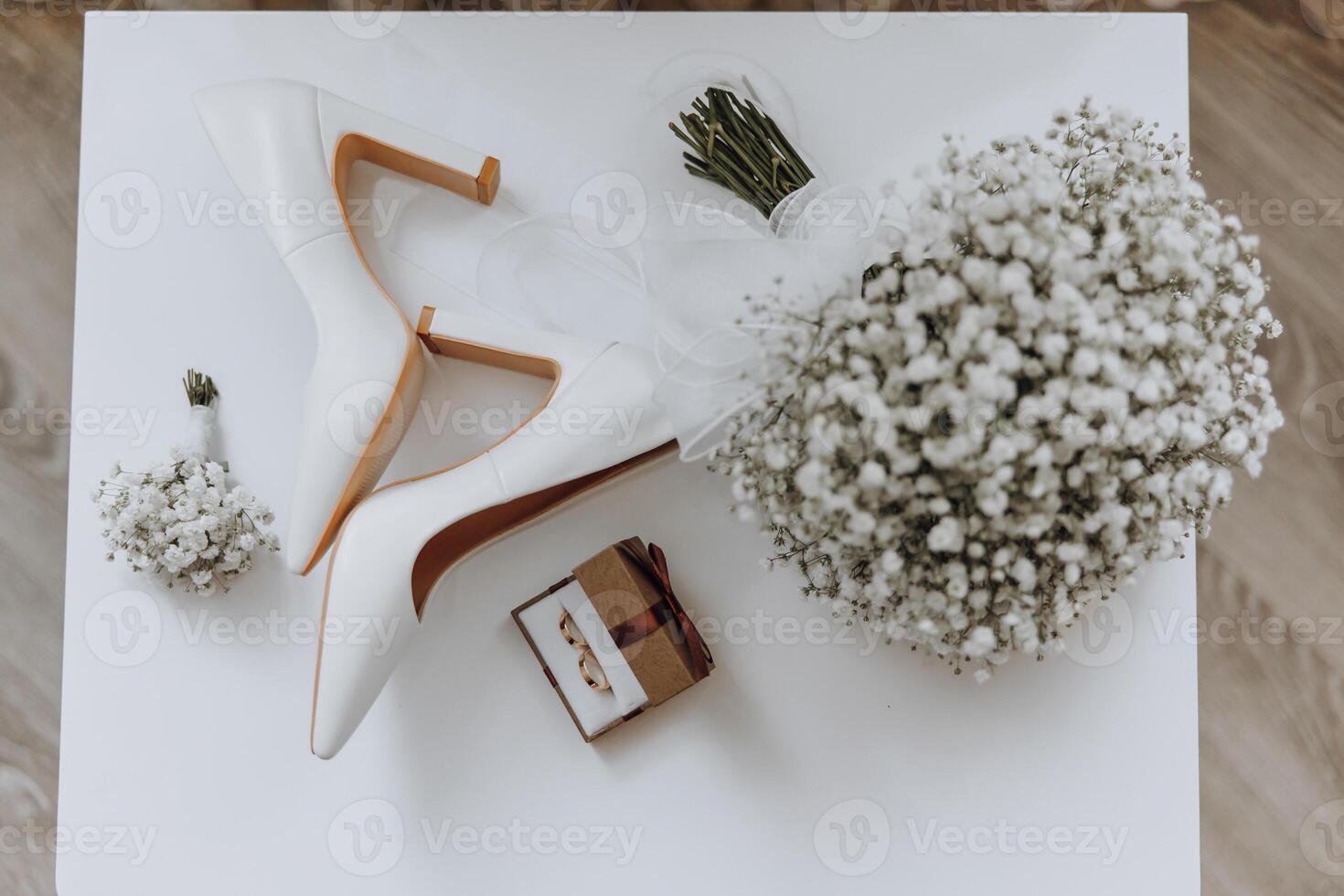 A pair of white shoes and a bouquet of white flowers sit on a table photo