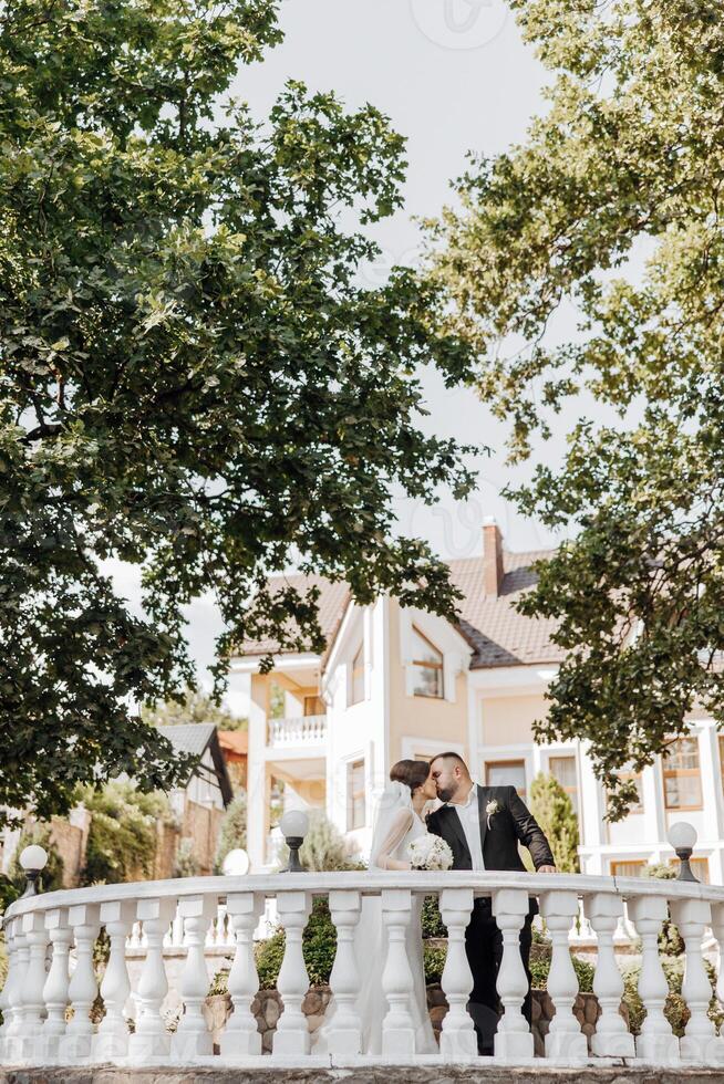 A couple kissing on a white railing in front of a house photo