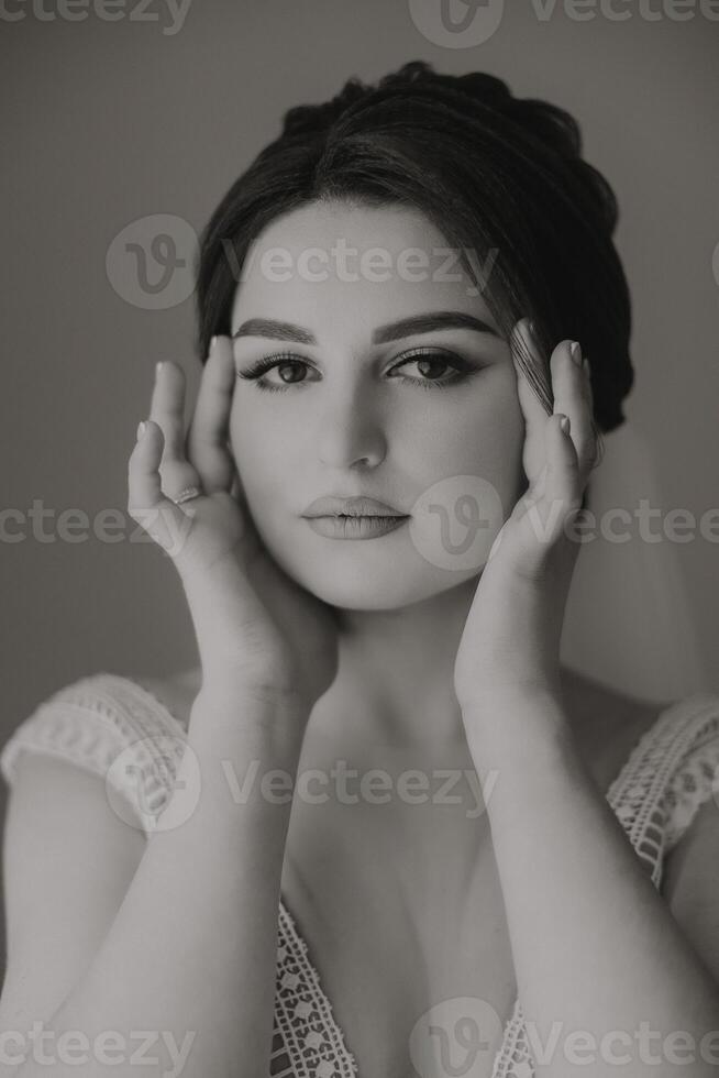 A woman with her hands on her face, looking at the camera photo