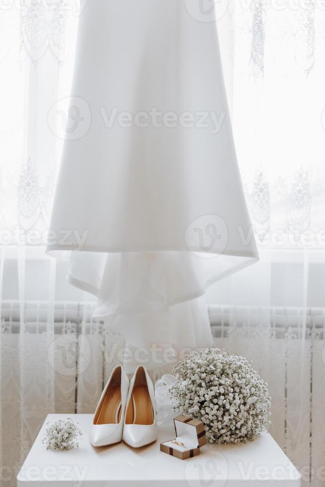 A pair of white shoes and a bouquet of white flowers are displayed on a table photo